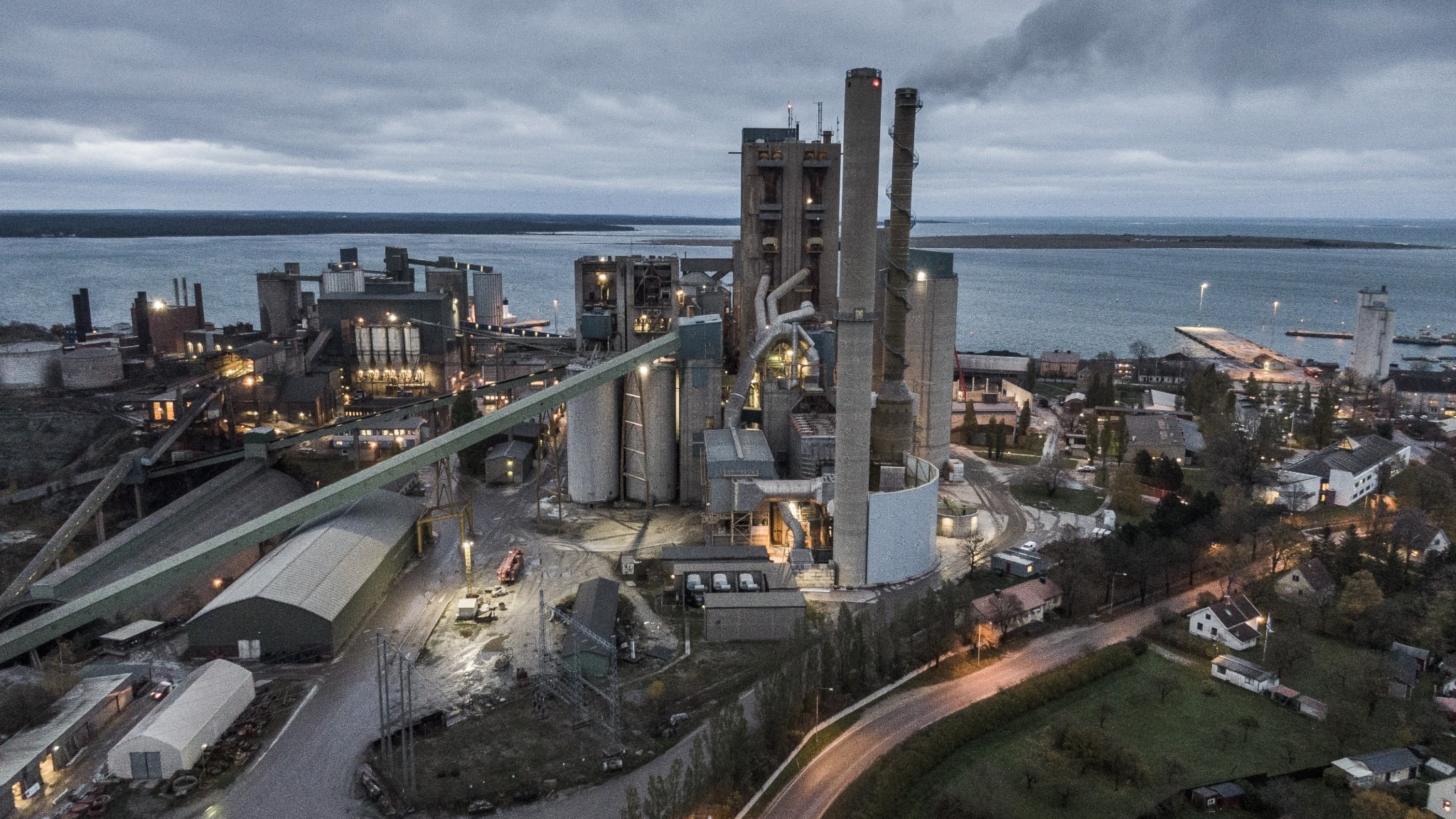 Cementfabrik med stora skorstenar som släpper ut tjock vit och grå industrirök